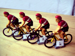 Une équipe de quatre cyclistes miniatures alignés, dossards numérotés